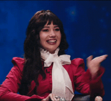 a woman wearing a red shirt and a white bow tie is sitting in a chair .