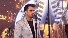 a man in a white jacket stands in front of a microphone in front of a sign that says cantando