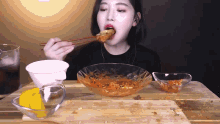 a woman is eating food with chopsticks from a bowl on a table