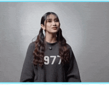 a woman wearing a black sweatshirt with the number 977 on it