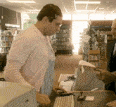 a woman in a pink sweater is standing at a counter in a library