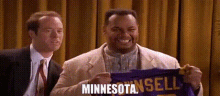 a man is holding a purple jersey that says minnesota .