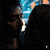 a close up of a man and woman kissing with the letter l on the bottom right