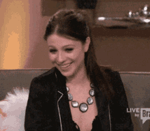a woman sitting on a couch with a live by bravo speech bubble behind her