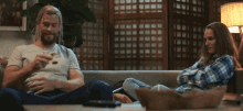 a man and a woman are sitting on a couch and the woman is covering her eyes