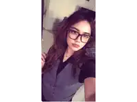 a woman wearing glasses and a vest is taking a picture of herself