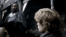 a man and a boy are standing next to each other in a dark room . the boy is looking at the man .