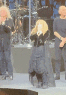 a group of people are standing on a stage and one of them is covering her mouth