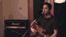 a man singing into a microphone while holding a guitar