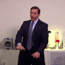 a man in a suit and tie is dancing in front of speakers
