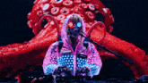 a woman in a pink jacket with the name austria on it stands in front of a red octopus