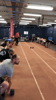 a group of people are squatting on a track in a gym