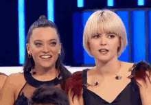 two women are standing next to each other on a stage in front of a crowd .
