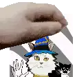 a cat wearing a blue hat is being held by a person 's hand .