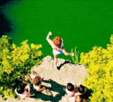 a group of people are looking at a woman jumping into a green lake