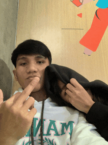a man wearing a miami sweatshirt is giving the middle finger to the camera