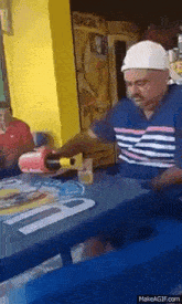 a man is pouring a drink into a glass at a table in front of a fridge that says skol