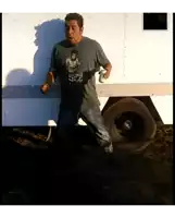 a man wearing a bruce lee t-shirt stands in front of a trailer