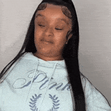a woman with long black hair and a pink hoodie is making a funny face .