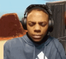 a man wearing headphones and a blue hoodie is looking down