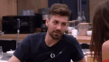 a man with a beard is sitting at a table next to a woman .