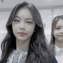 two girls are standing next to each other and one of them has a piercing in her ear .