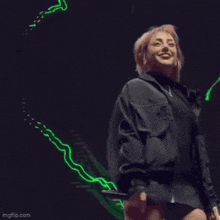 a woman is holding a microphone on a stage in front of a green light .