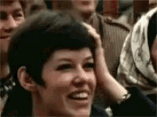 a woman is holding her head in a crowd of people .