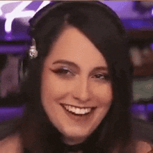 a woman wearing headphones is smiling in front of a computer screen .
