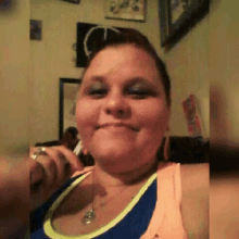 a woman is taking a selfie in a living room while wearing a blue and yellow tank top .