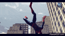 a spider-man is doing a handstand in front of a building with makeagif.com at the bottom of the screen