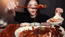 a woman is eating a plate of food with a spoon in her mouth