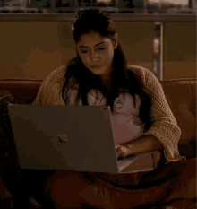 a woman sits on a couch with a laptop
