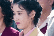 a close up of a woman 's face with a pink shirt and a yellow jacket
