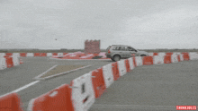 a car is driving through a parking lot with thinki jules on the bottom right