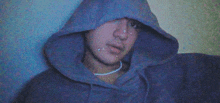 a man in a blue hoodie with a necklace around his neck