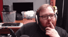 a man with a beard wearing headphones has his finger on his mouth