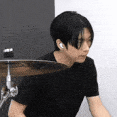 a young man in a black shirt is playing drums in a room .