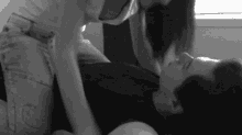 a black and white photo of a woman kissing a man on the floor .