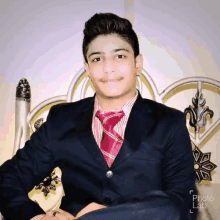 a young man in a suit and tie is sitting on a chair