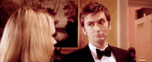 a man in a suit and bow tie is looking at a woman in a dress .