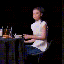 a woman is sitting at a table and giving a thumbs up .