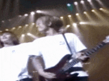 a man is playing a guitar on a stage while a woman sings .