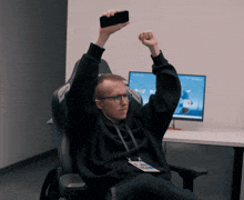 a man sitting in a chair holding up a phone that says akracing
