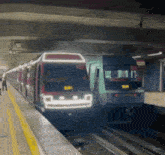 a subway train is pulling into a station while another train is waiting on the platform .