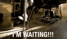 a person sitting at a desk in a classroom with the words `` i 'm waiting !!! ''