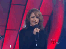 a woman singing into a microphone with the letter l on the bottom
