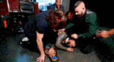 a group of men are kneeling around a wrestler with a belt on his head