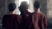 three men in red shirts are standing next to each other .