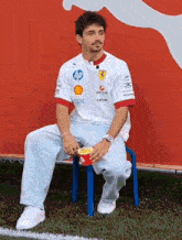 a man sitting on a blue chair with a box of popcorn in his hand